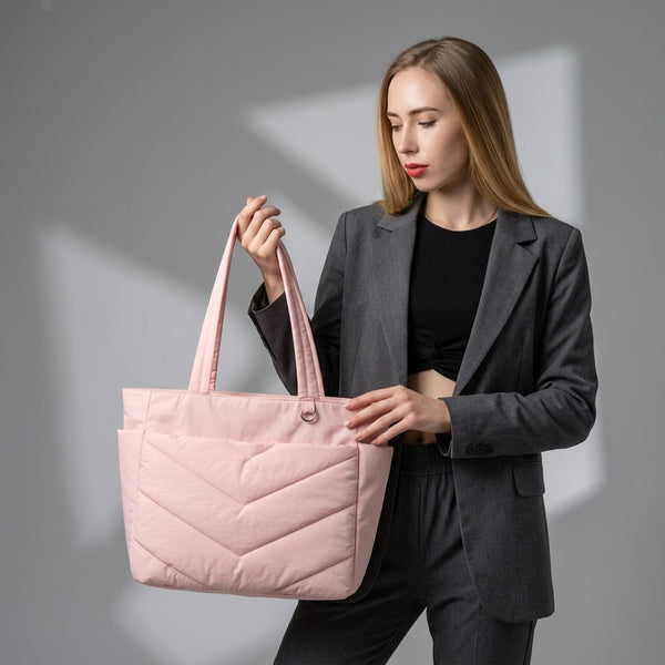 Woman holding a pink quilted tote bag against a gray background