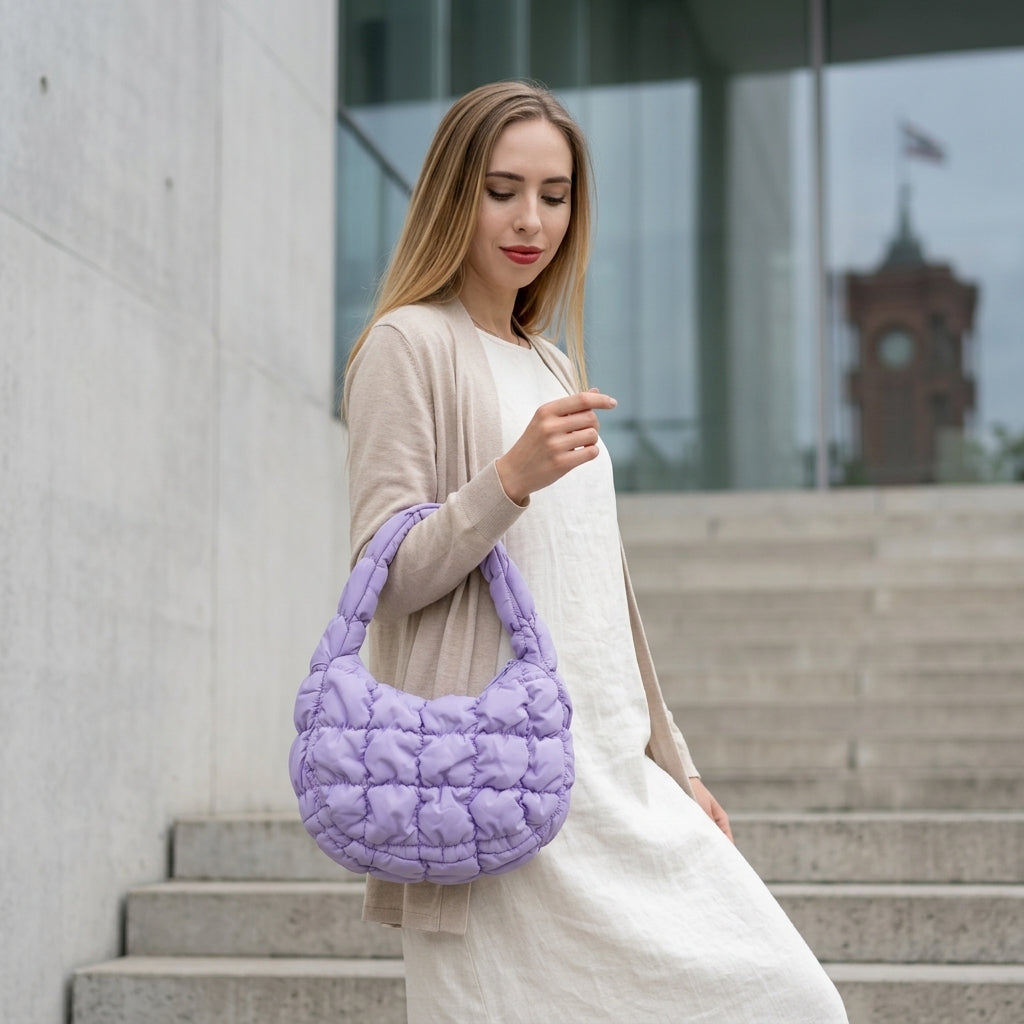 Woman holding a purple quilted handbag outdoors on steps.