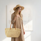 Woman wearing a beige hat and holding a matching straw bag against a white background