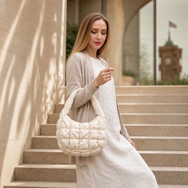 Beige Puffy Quilted Hobo bag carried by model on warm stone steps